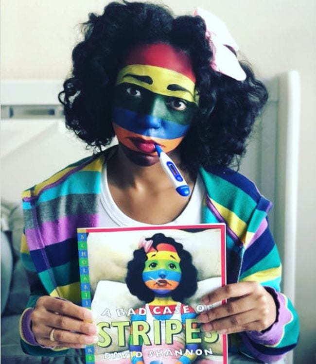 Book Character Costume Ideas Bad Case of Stripes Woman with her face painted in colorful stripes and a thermometer in her mouth, holding A Bad Case of Stripes- book character costume