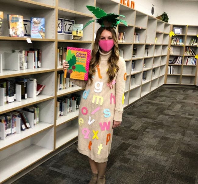 Book Character Costume Ideas Chicka Chicka Boom Boom Woman wearing palm leaves on her head and covered in alphabet letters, carrying the book Chicka Chicka Boom Boom- book character costume