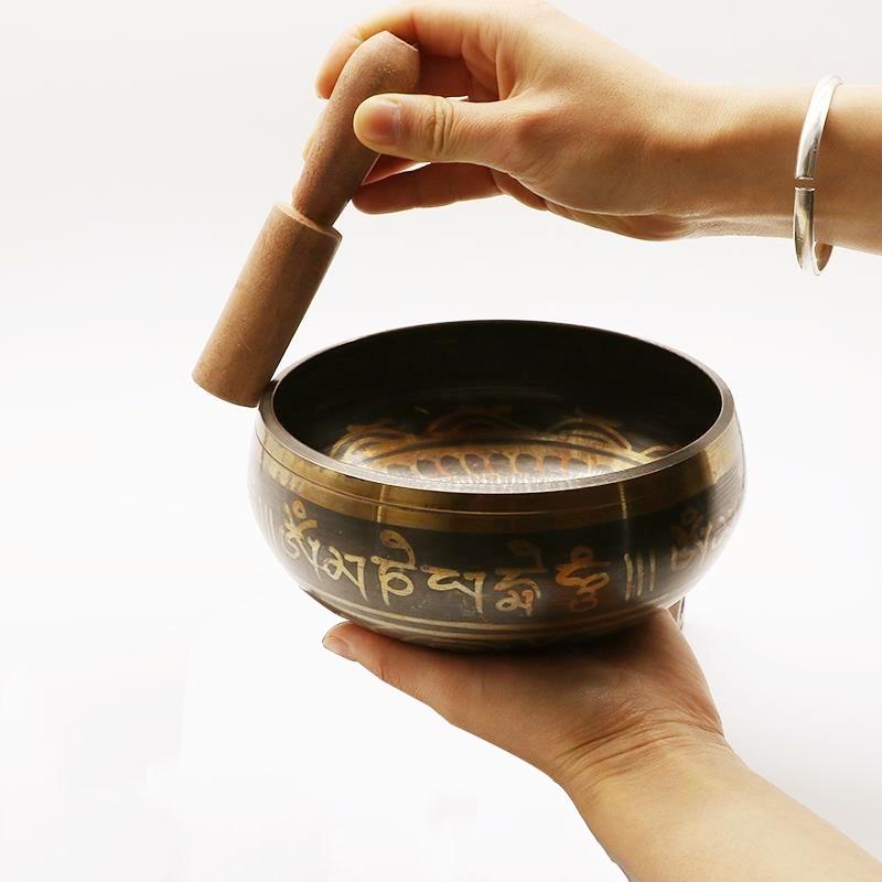Golden Moment A woman holds a singing bowl in one hand, and with the other runs the striker around the edge