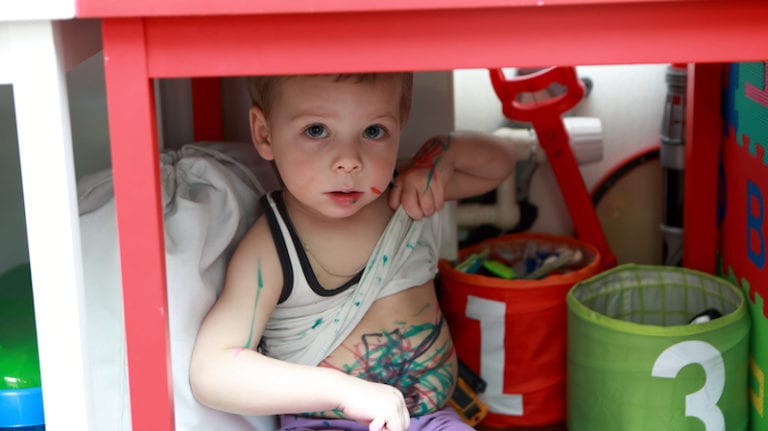 Portrait of boy covered in paint under table - incoming kindergarteners need key life skills