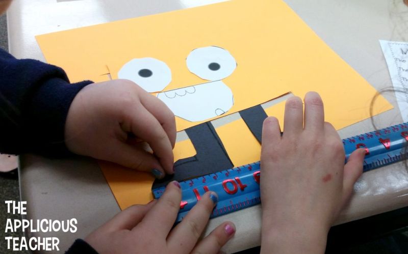 Children measuring the parts of a monster made out of construction paper