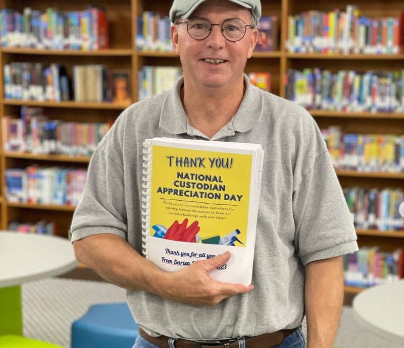 National Custodian Day Book Custodian holding a spiral-bound book of thank you notes