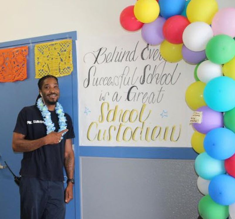 National Custodian Day Decorations School custodian standing by a sign and balloons celebrating National Custodian Day