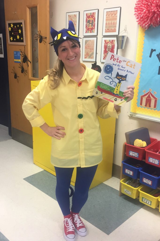 Pete the Cat A woman is shown holding a Pete the Cat book. She is wearing a yellow button up shirt and signature red sneakers. She is wearing a pete the cat headpiece.