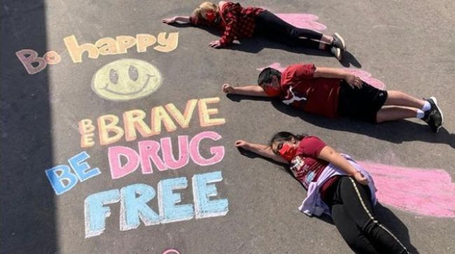 Red Ribbon Week Ideas: Chalk Drawings Three students lying by a chalk drawing saying Be happy, be brave, be drug-free (Red Ribbon Week Ideas)