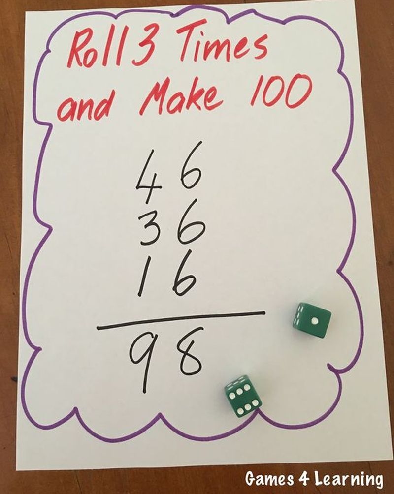 Whiteboard with a pair of dice. Text on board reads Roll 3 and Make 100, followed by a sum of 46+36+16=98.