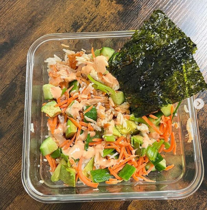 Square glass container containing salad with smoked salmon and seaweed chips