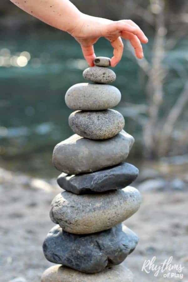 Stacked Rocks A small hand places a small stone at the top of a stack of rocks