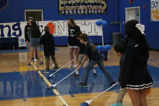 Sweep the Potato Pep rally activities include the one shown where students are sweeping a potato across a gym floor