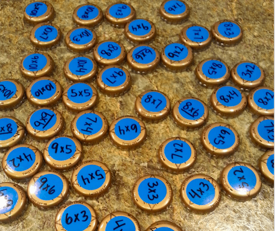bottle-cap-multiplication Bottle caps with multiplication problems written on top to teach multiplication