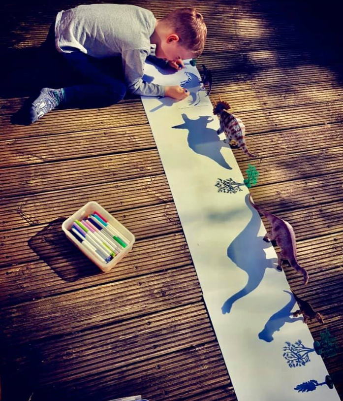 Boy tracing dinosaur with shadow