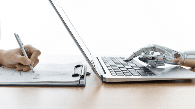 Photo of a human hand writing with a stylus on a laptop juxtaposed with a robot hand typing on a laptop