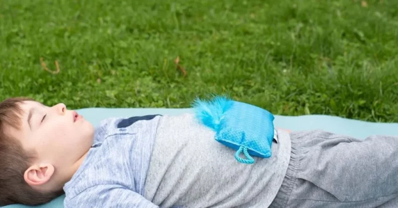 Belly Breathing A young boy lays in a field with a pillow on his belly